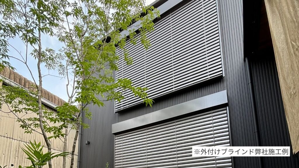 黒いガルバリウム外壁の高気密高断熱住宅に設置された外付けブラインドの施工例。夏の強い日差しを遮蔽し、室内の快適な温度を保つ。