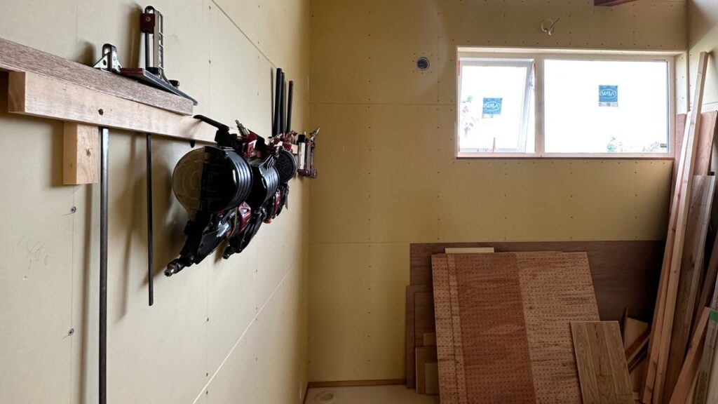 くらはし建築の工事現場。壁に設置された棚に、大工の釘打ち機などの工具が整理整頓されている様子。