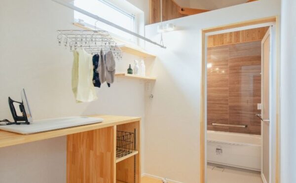 岡崎市の工務店、くらはし建築の注文住宅、エアコン付き脱衣所兼ランドリールームの施工事例。天井の物干し竿に干された洗濯物が、寒い冬の時期や梅雨の時期でもカラッと乾く様子。家事ラクと快適な部屋干しを実現する空間デザイン。