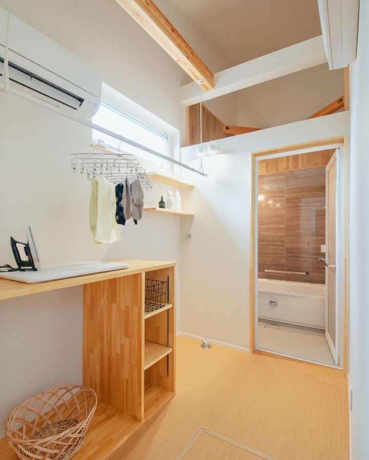 岡崎市の工務店、くらはし建築の注文住宅、エアコン付き脱衣所兼ランドリールームの施工事例。天井の物干し竿に干された洗濯物が、寒い冬の時期や梅雨の時期でもカラッと乾く様子。家事ラクと快適な部屋干しを実現する空間デザイン。