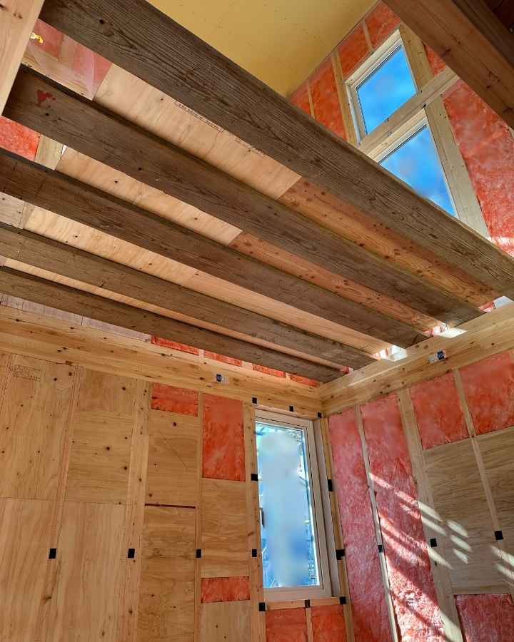  吹き抜けを見上げたアングル。窓から差し込む自然光で、照明がなくても明るい建築中の室内。