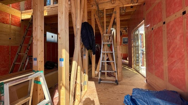  建築中の室内風景。壁一面に隙間なく施工された断熱材と、頑丈な木造構造体。