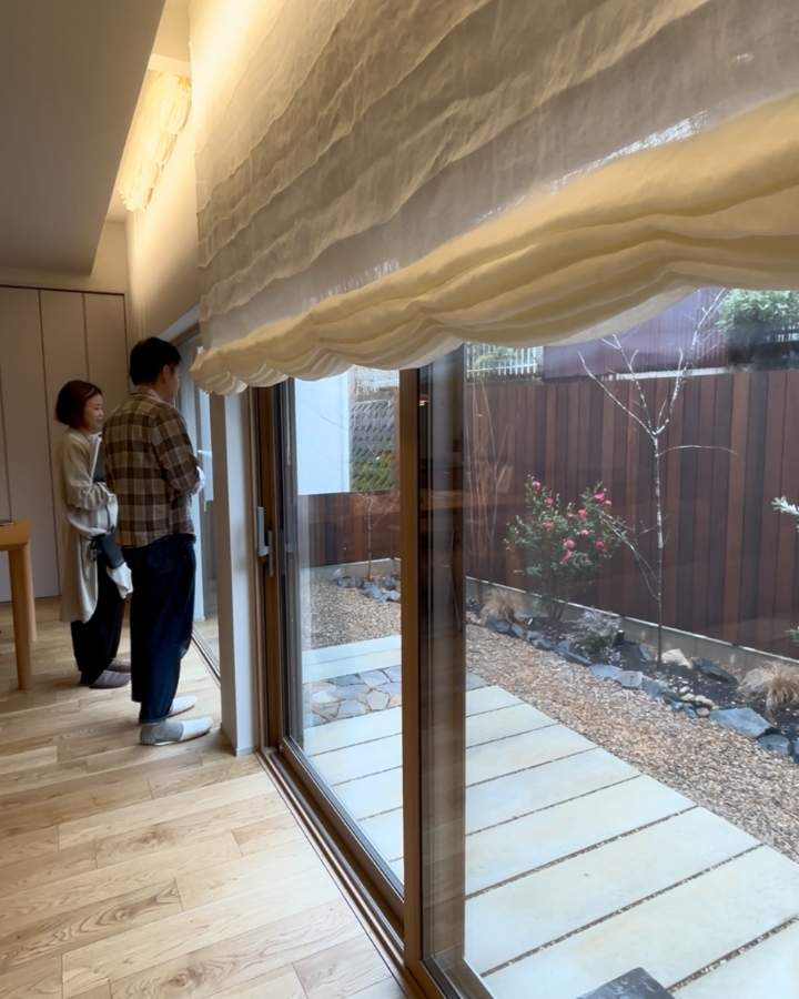 リビングからプライベートな庭を眺めるお客様たち 視線を遮るウッドフェンス