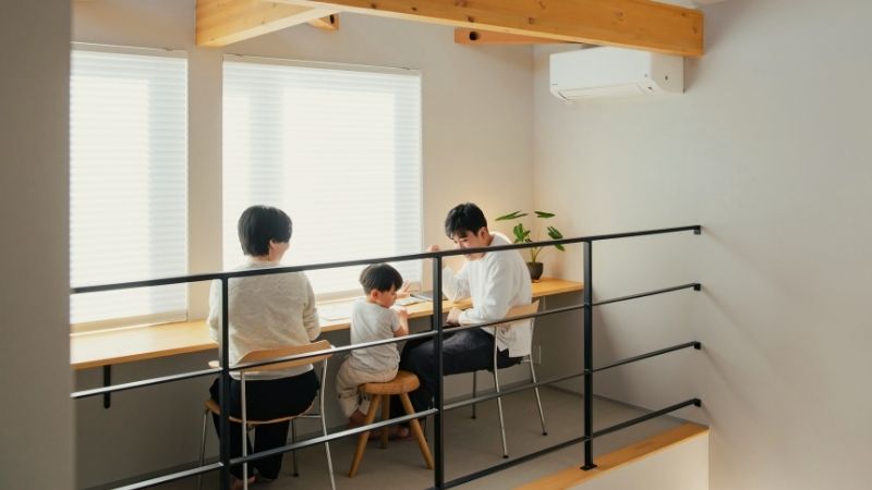 高断熱性能により結露のない窓際や吹き抜け空間でも、寒さを感じず快適に過ごしている家族の様子。