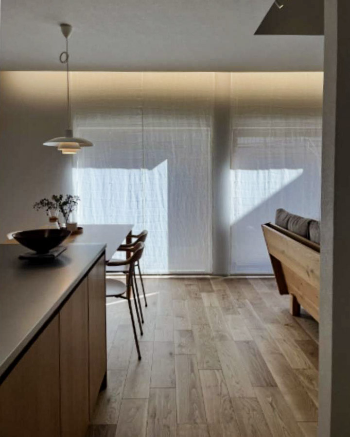 北欧デザインのペンダントライトと、レースのカーテン越しに広がる柔らかな自然光。心地よいダイニング空間。
