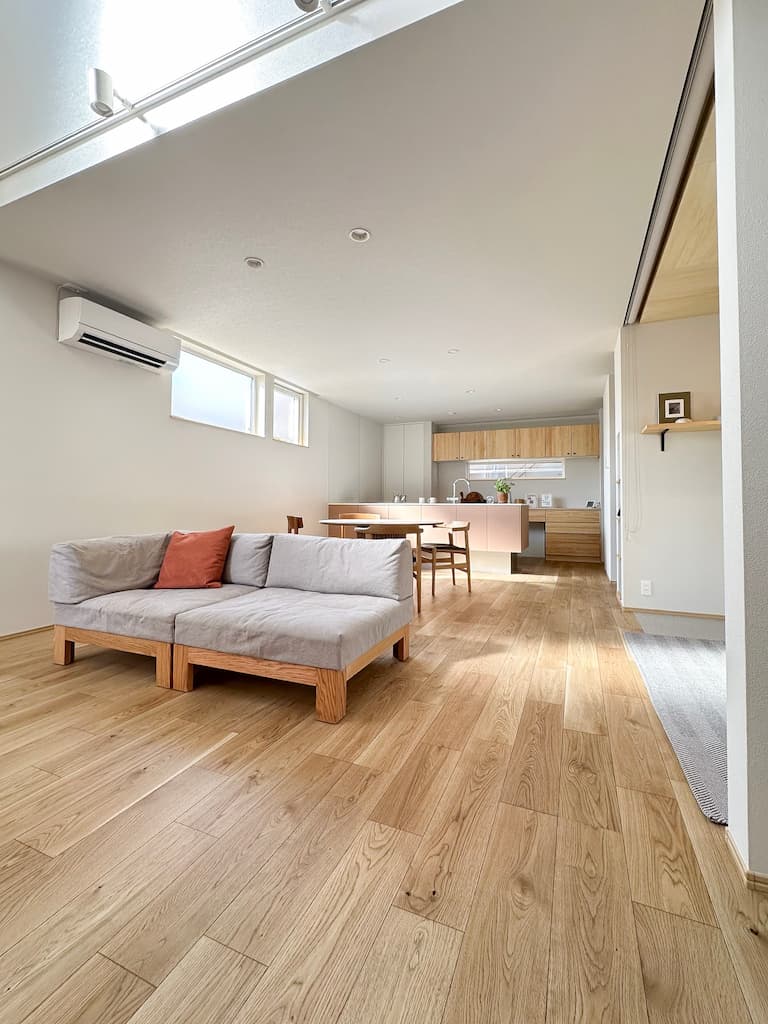 吹き抜けから明るい光が差し込む広々としたLDK。無垢の床と、家事がスムーズに進むフラットな対面キッチンが印象的な開放感あふれる住まい。