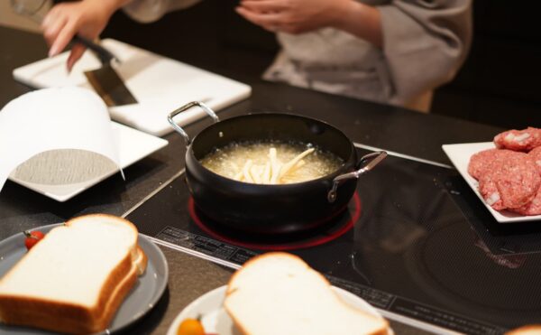 くらはし建築のコンセプトハウスに採用された、パナソニック製のトリプルワイドIHクッキングヒーター。天板との段差が一切ないフラット設計により、調理スペースを広く活用でき、お皿や食材を気軽に置ける機能的なキッチンの様子。