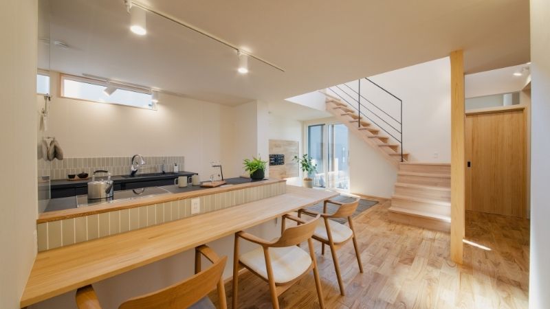 レンジフード（換気扇）をなくした、くらはし建築の開放的なアイランドキッチンとリビングの全景。視線を遮るものがないため、LDK全体が広く、明るく感じられる空間デザイン。